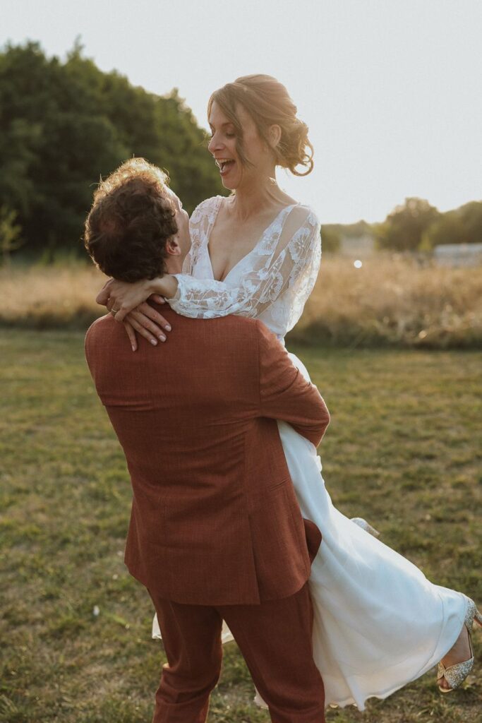 Le marié soulève la mariée dans ses bras au coucher du soleil, mariage en Touraine