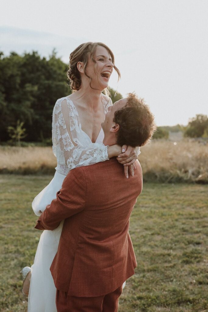 Les mariés riant dans un champ au coucher du soleil, mariage en Touraine accompagné par Épure Event