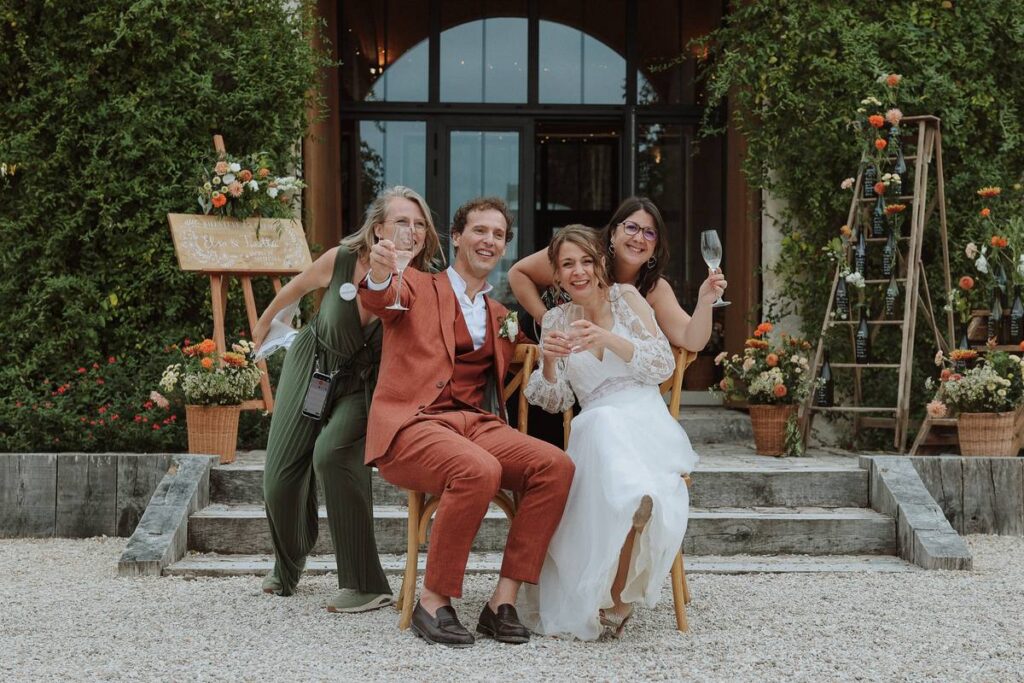 Les mariés trinquent avec leur wedding planner Épure Event et son assistante devant le domaine du Grand Breuil, mariage en Touraine
