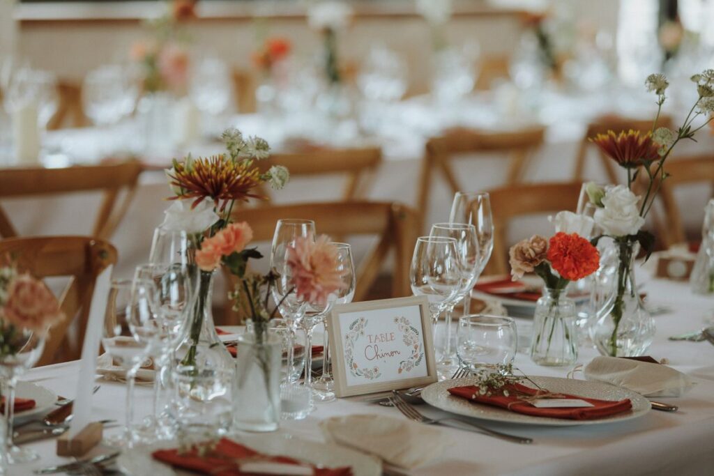 Nom de table « Chinon » illustré par La Cocotte en Carton, entouré de soliflores sur la table du dîner, mariage en Touraine