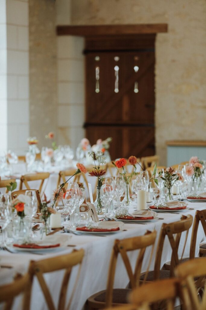 Tables du dîner décorées de fleurs en soliflores dans la salle de réception, mariage en Touraine